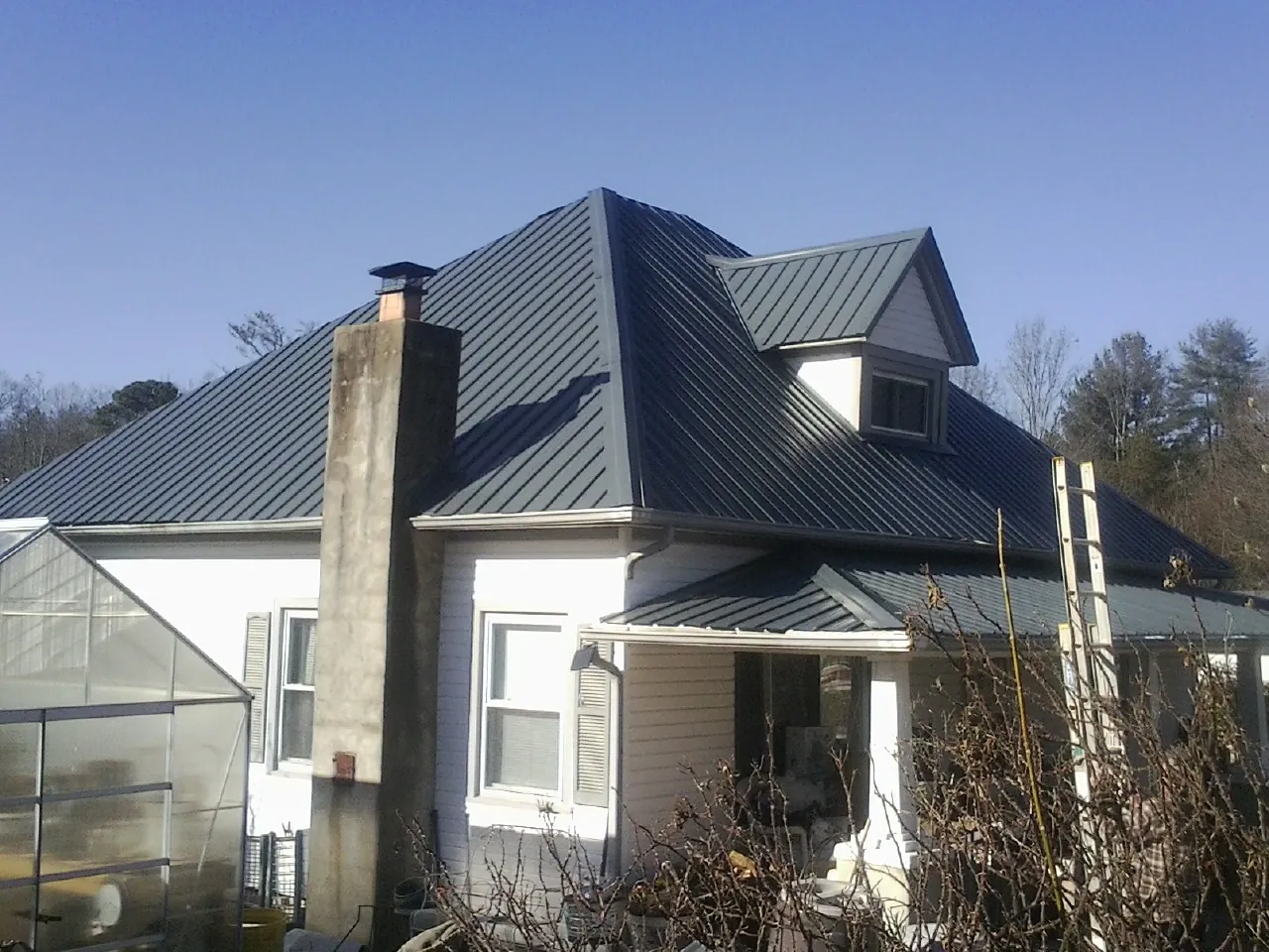 Dark blue standing seam metal roof on a white farmhouse with dormer — Slate & Tile Roof Repair by Roofing Brothers in Alsea