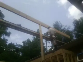 Carpenter setting a ridge beam over a new addition frame — Ice Dam Removal by Roofing Brothers in Alsea