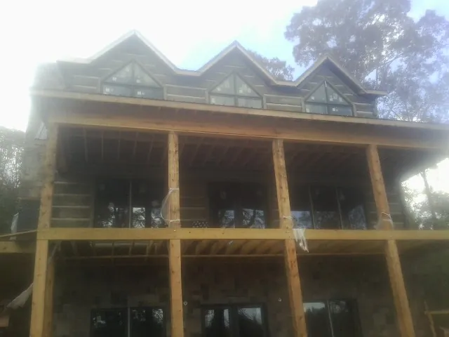 Dormers and porch framing on a large log home under construction — Roof Coating work by our crew in Alsea