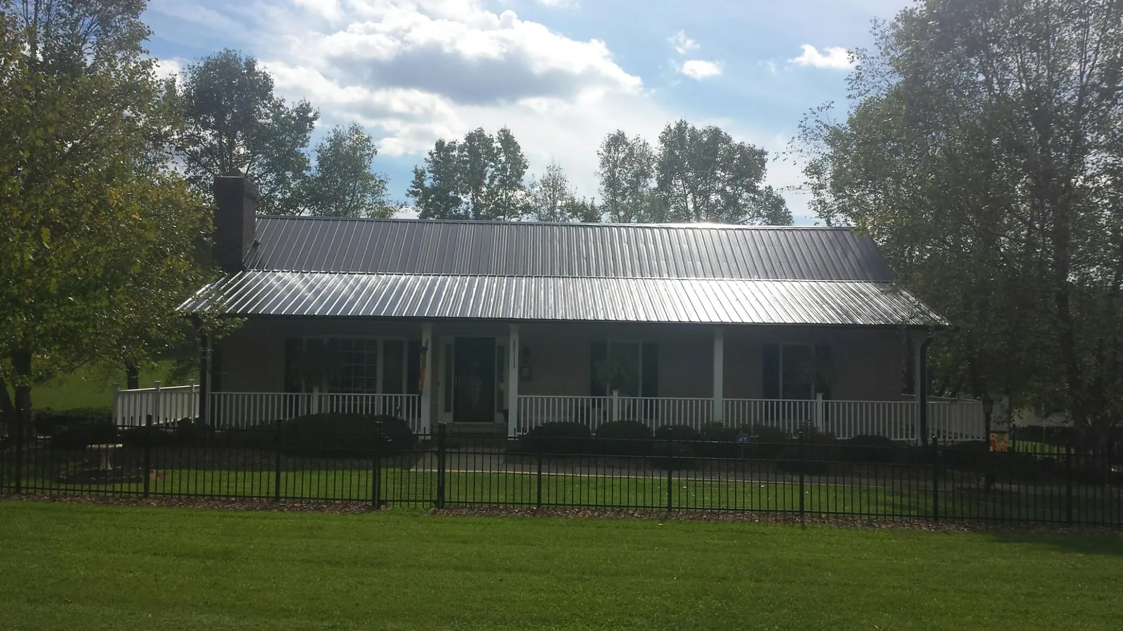 Gray metal roof on a brick ranch with a full width front porch — Gutter Guard Installation work by our crew in Alsea