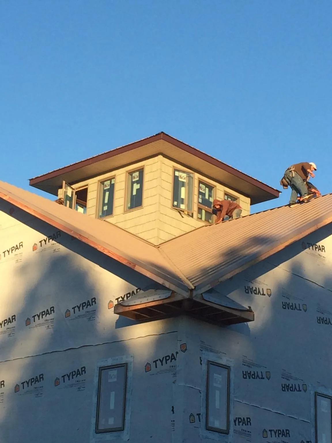 Roofers working around a rooftop cupola on a new metal roof at sunset — Roof Waterproofing in Alsea by Roofing Brothers